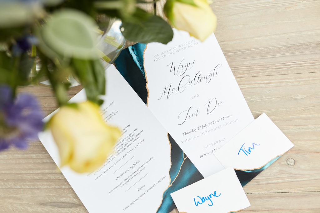 Wedding stationery and name cards beside yellow roses