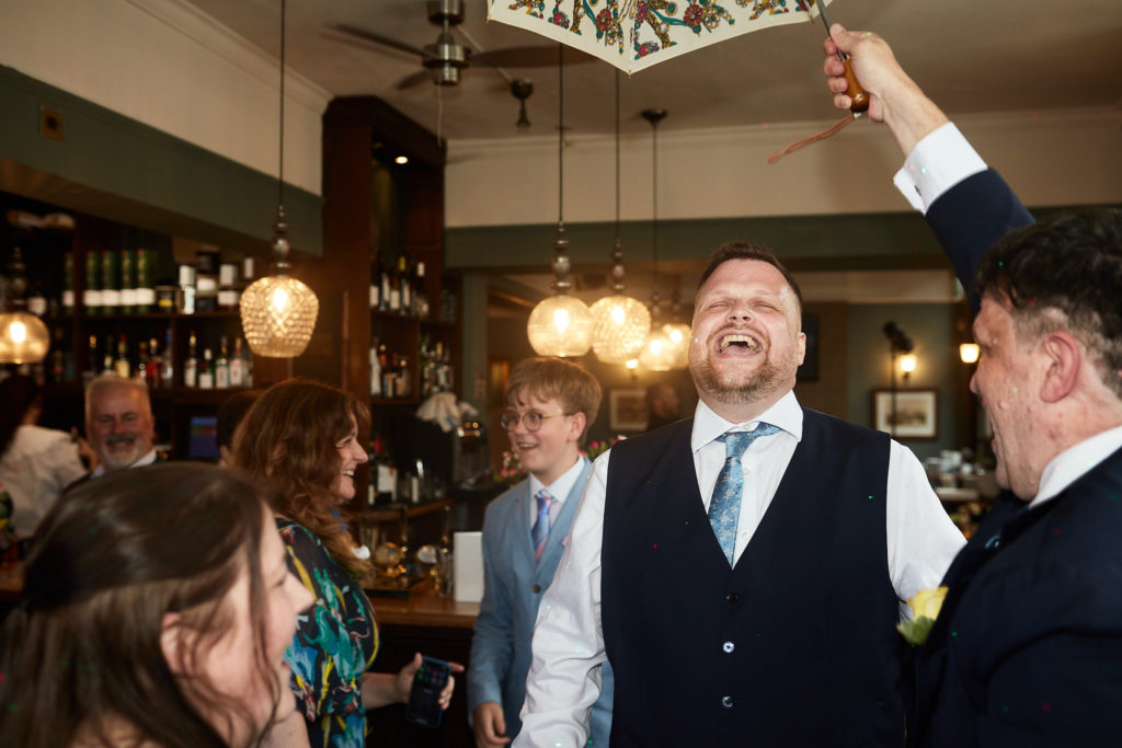 Groom laughing on the dance floor with his arm raised