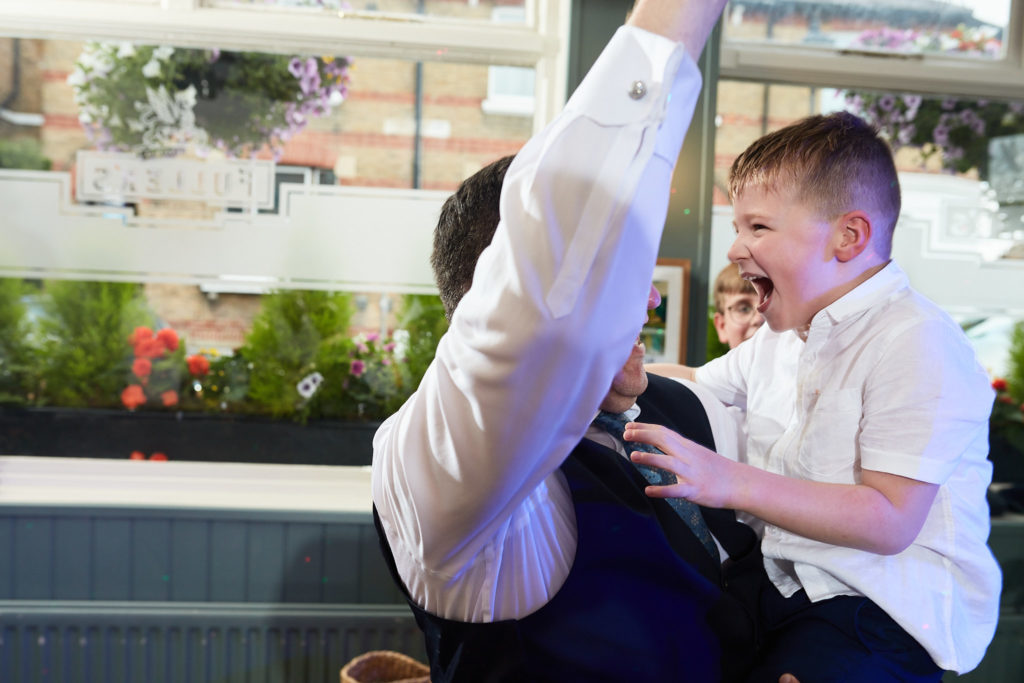 Young page boy laughing as he plays with a guest