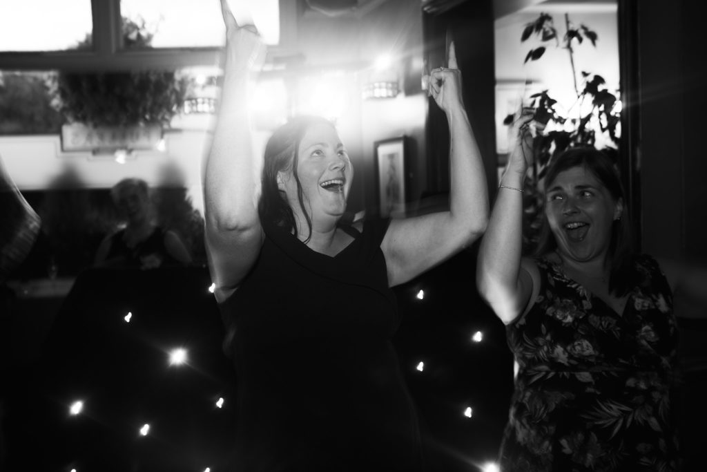 Black and white photo of a guest dancing with her arms in the air