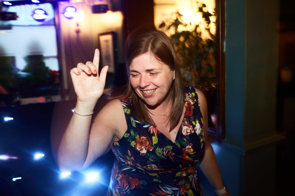 Guest in a floral dress dancing with her hand raised