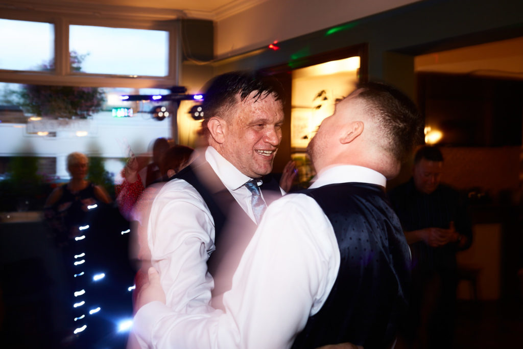 Two grooms dancing together in their waistcoats
