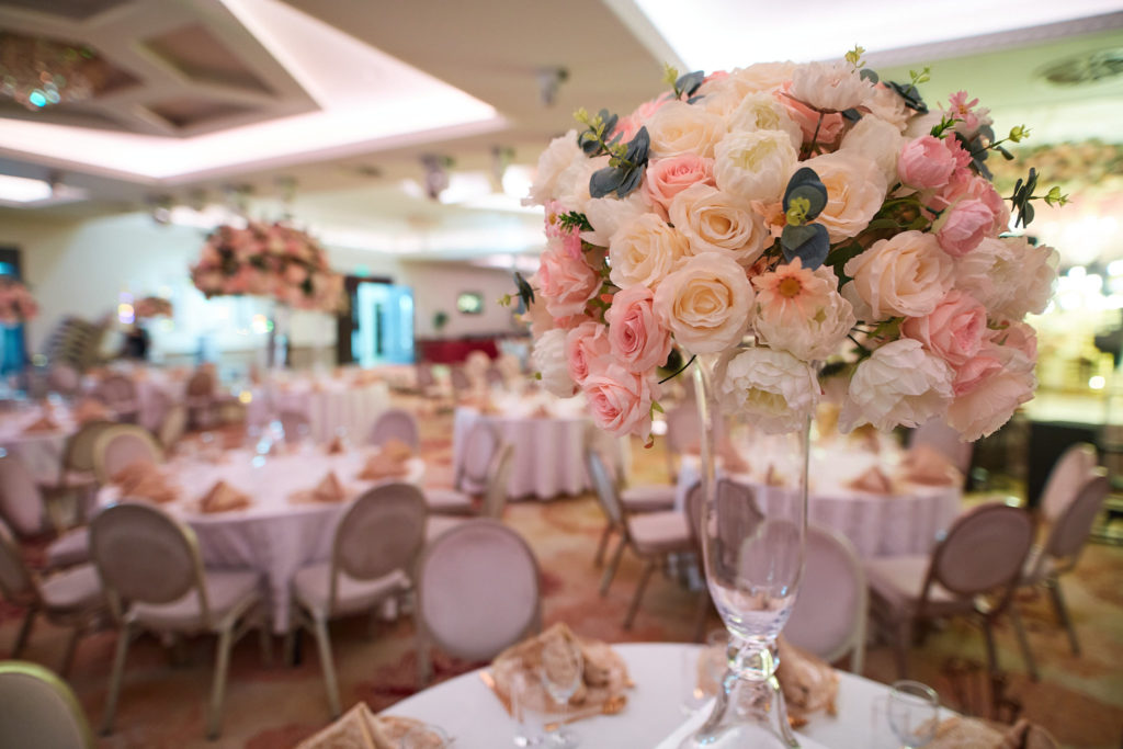 Reception hall with a tall centrepiece of blush and cream roses