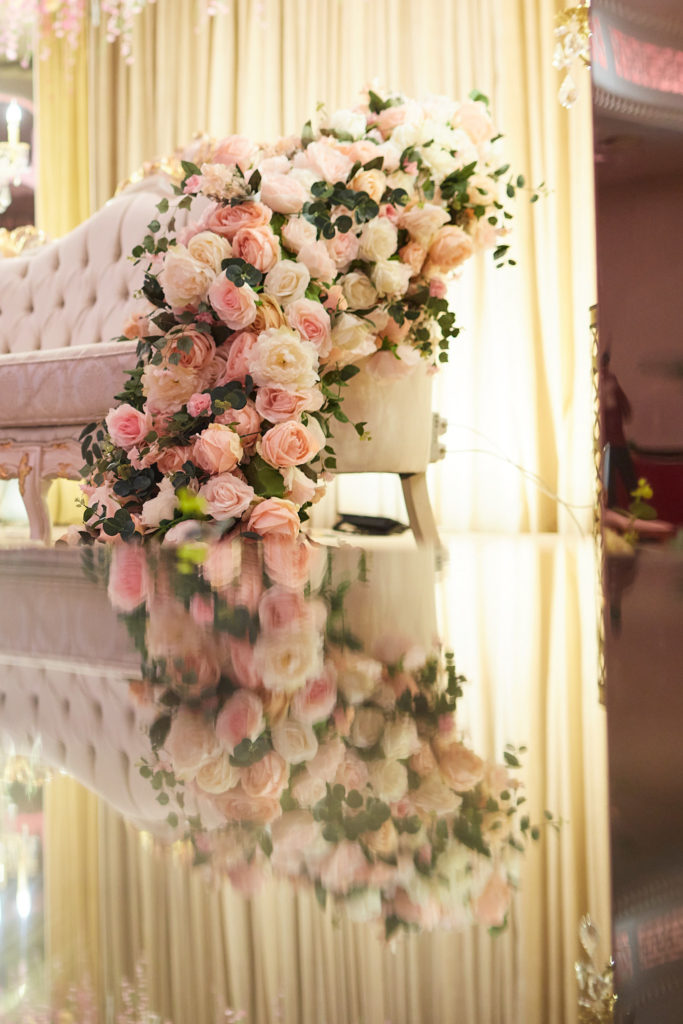 Cascade of pink and cream roses on a white sofa reflected in a mirrored floor