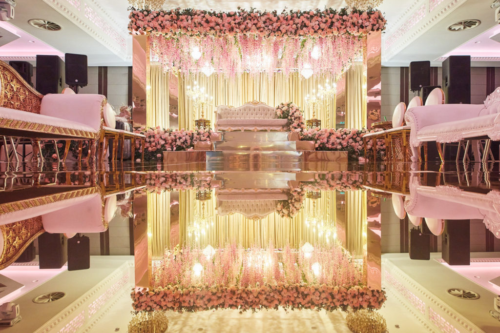 Wide view of the wedding stage and its floral canopy across the mirrored dance floor