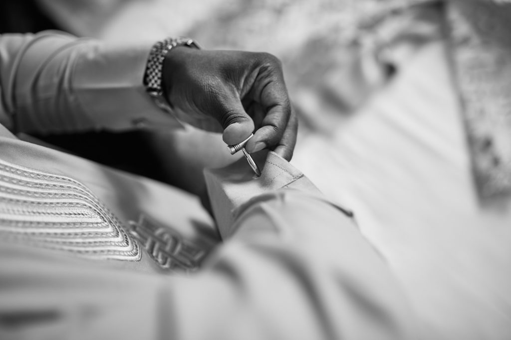 Black and white close-up of hands fastening a traditional outfit