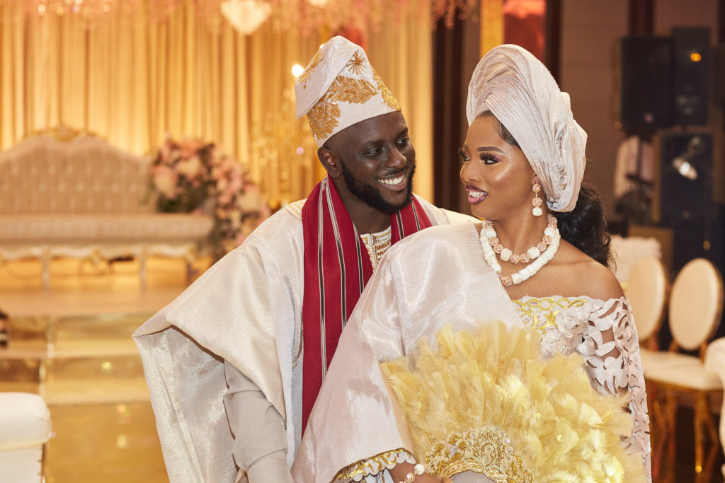 Bride and groom laughing together in cream and gold traditional attire