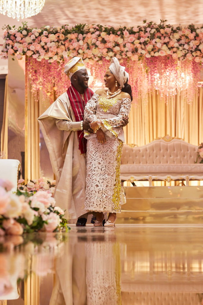Bride and groom laughing on the mirrored stage beneath hanging pink blossom