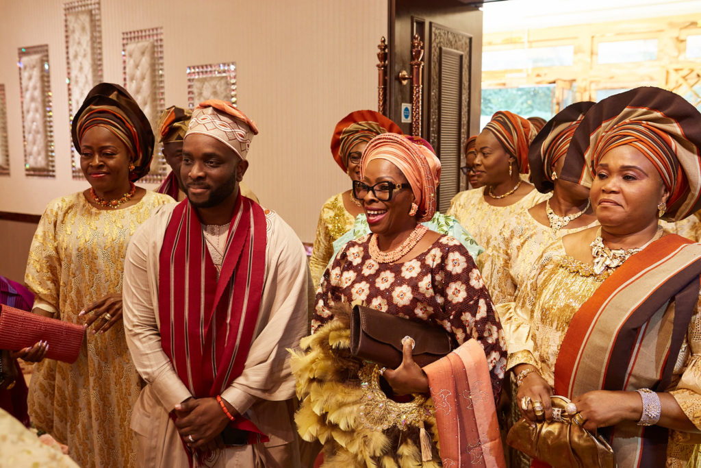 Family members in matching gold and burgundy traditional outfits arriving at the wedding