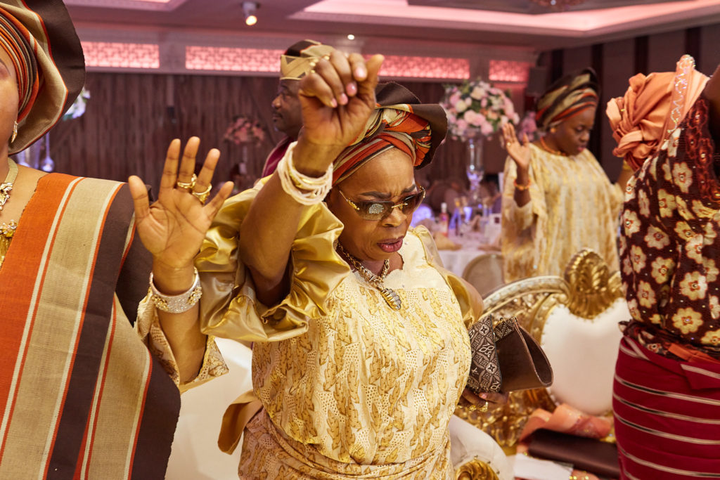 Guest in a gold lace outfit dancing with her hand raised
