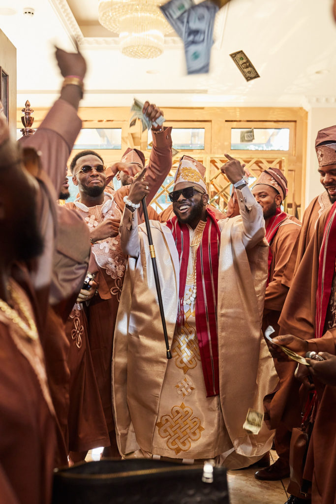 Groom dancing in with his groomsmen as banknotes are thrown in the air
