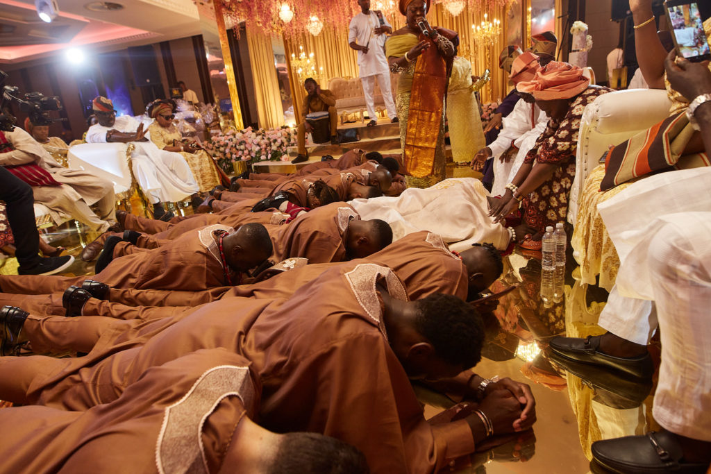 Groom and groomsmen lying face down on the floor before the bride's family