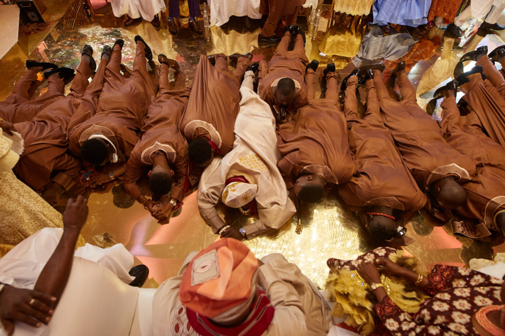 Groomsmen in matching brown outfits prostrating during the traditional wedding ceremony