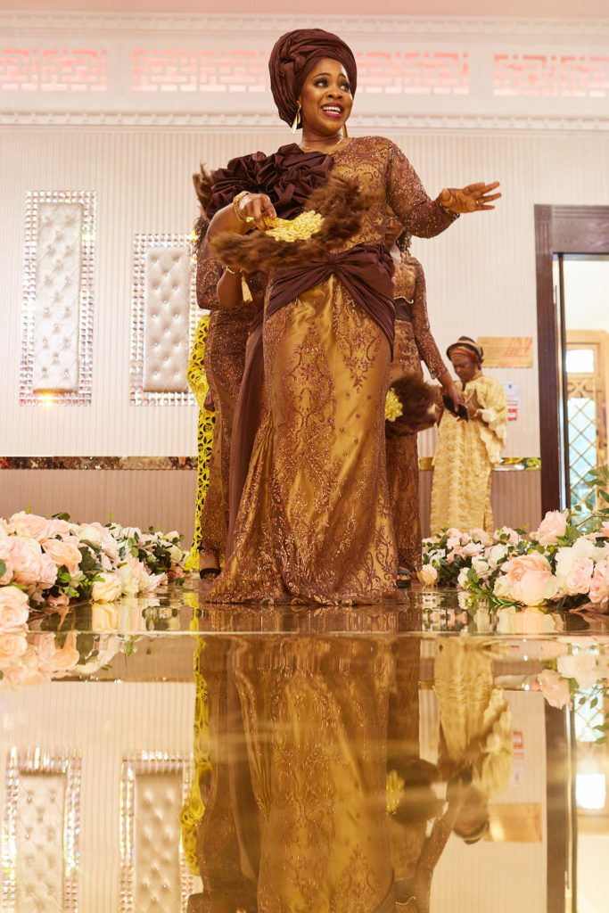 Woman in a bronze lace outfit and head tie dancing on the mirrored stage