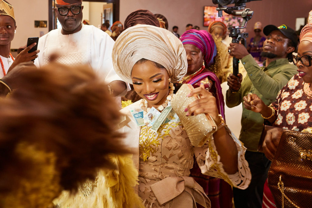 Bride smiling in a cream head tie as she dances in among her guests