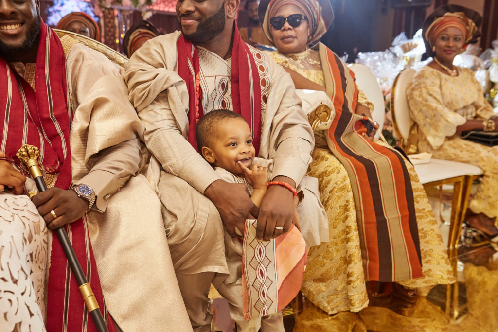 Groom sitting with a toddler on his knee among his groomsmen