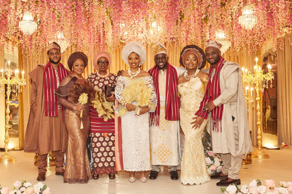 Bride and groom with family on the stage beneath a canopy of pink flowers
