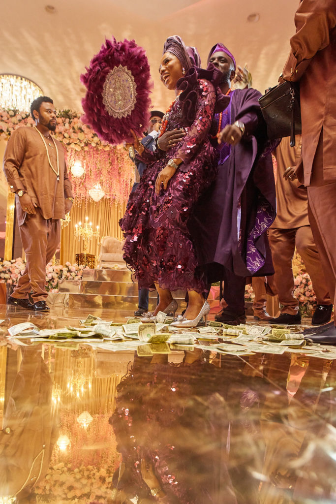 Bride in a purple sequinned outfit dancing with a feather fan as banknotes cover the floor