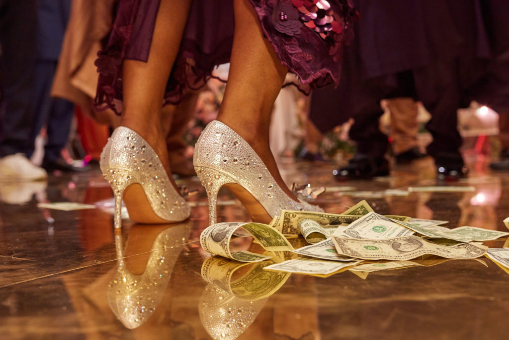Close-up of the bride's jewelled heels on a floor scattered with banknotes