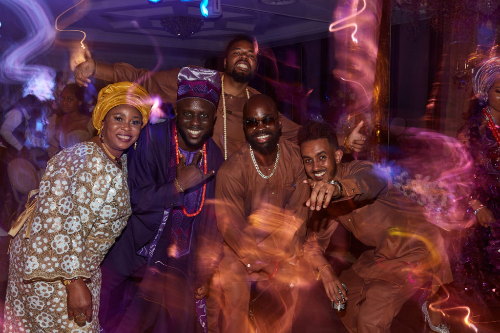 Wedding guests posing together on the dance floor under purple lights