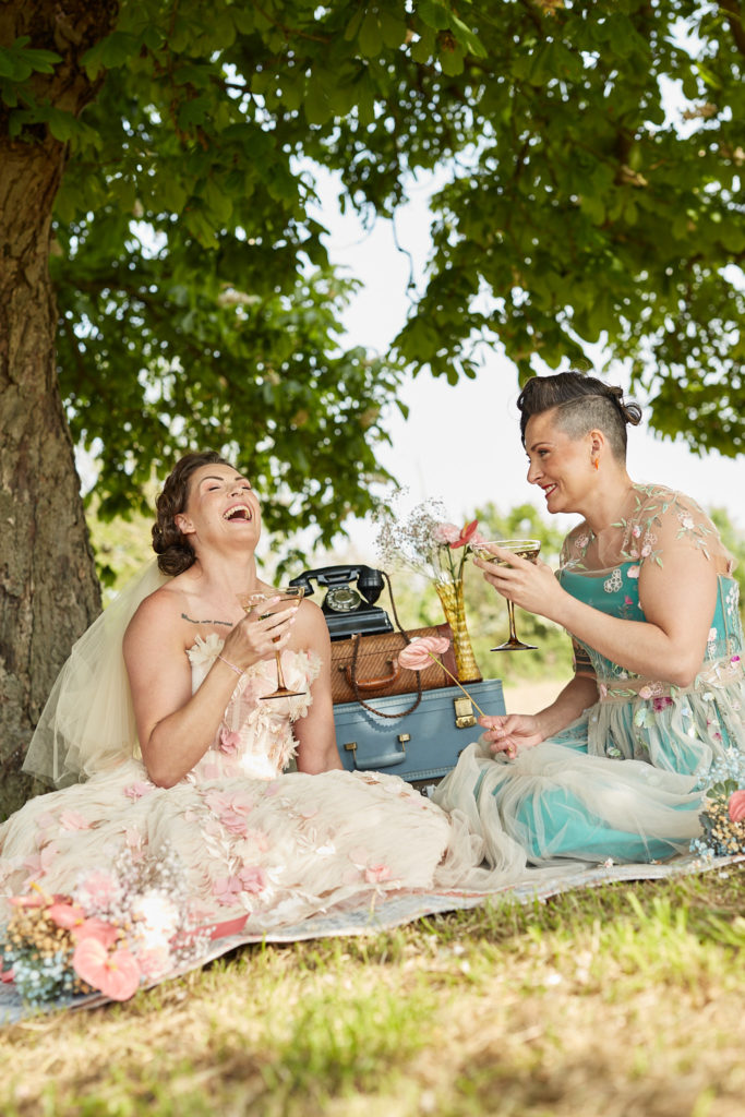 Bride laughing with her head thrown back at a picnic with her wife