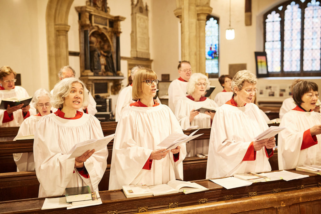 Church choir in white and red robes singing during the wedding service