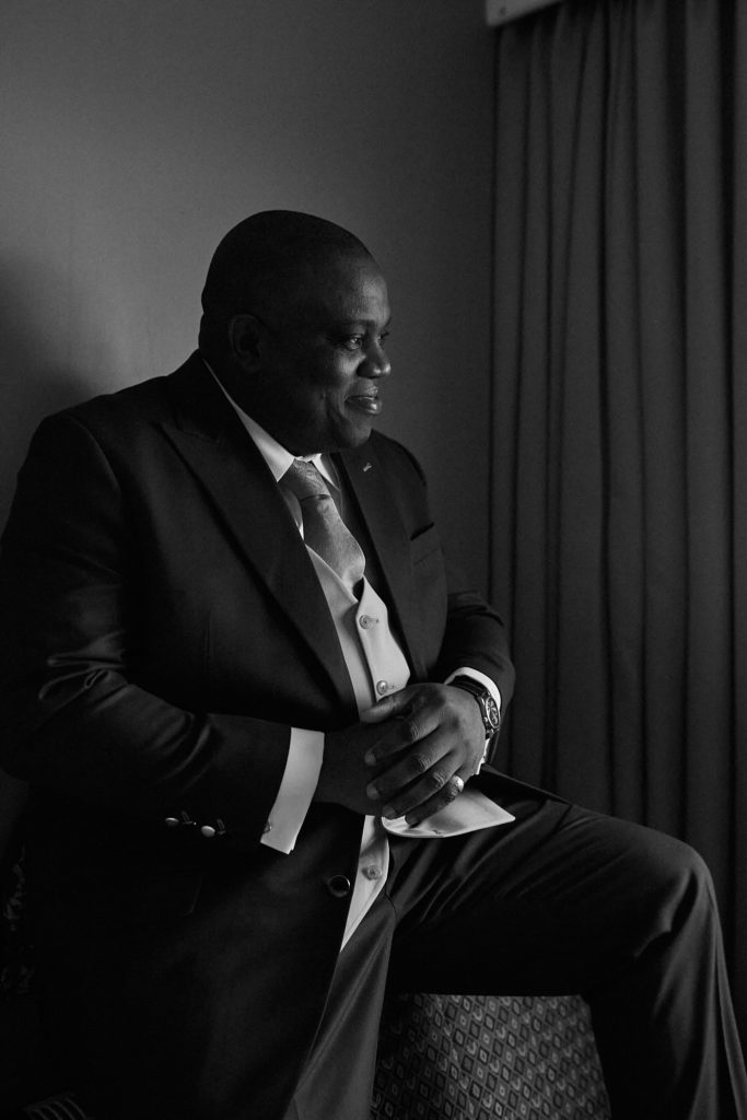 Groom sitting in shadow beside a window, looking out