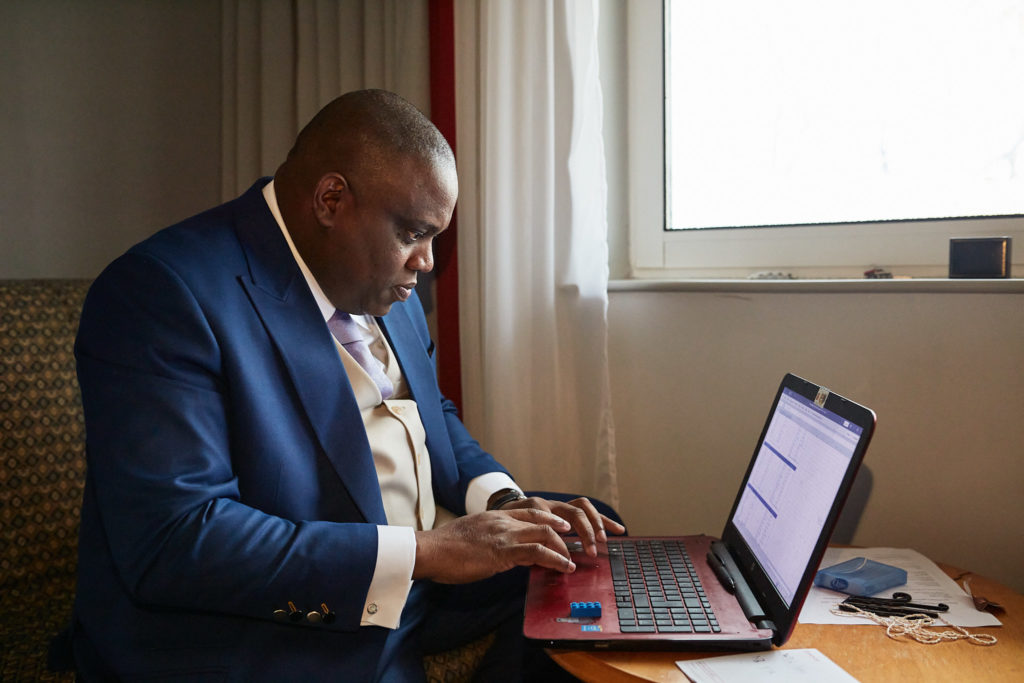 Groom working at a laptop in his suit on the wedding morning
