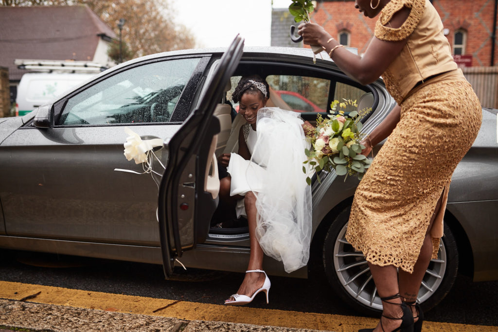 Bride stepping out of the wedding car with her bouquet