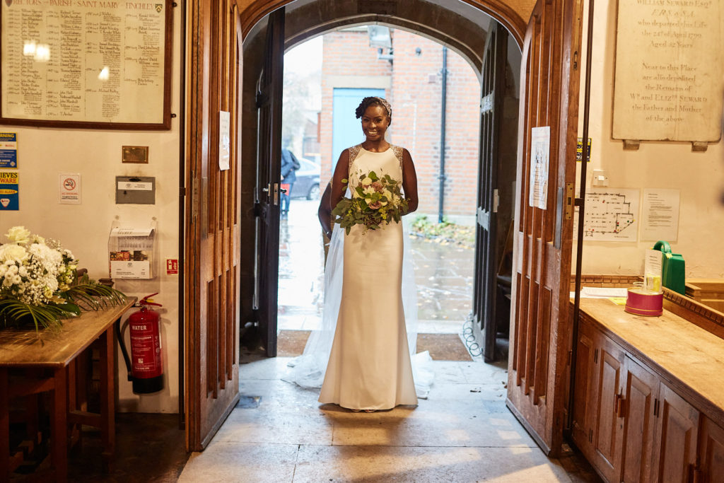 Bride standing in the church doorway with her bouquet before her church wedding in north-west London