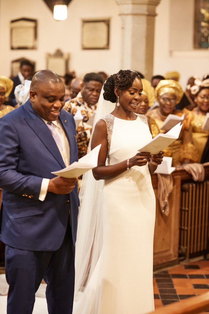 Bride and groom singing a hymn from their orders of service