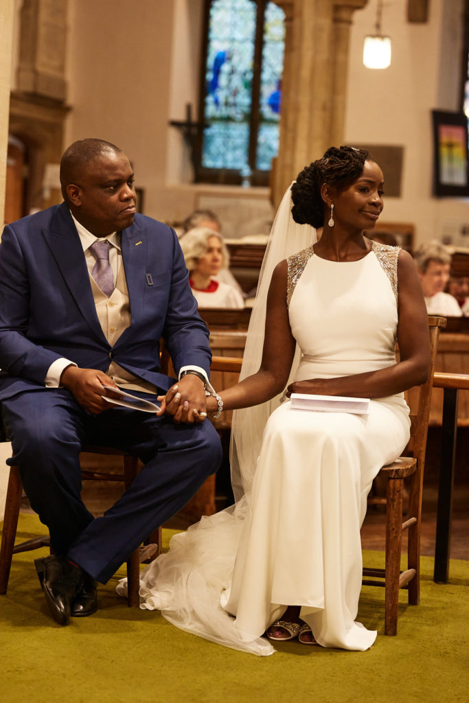 Bride and groom holding hands as they sit together in church