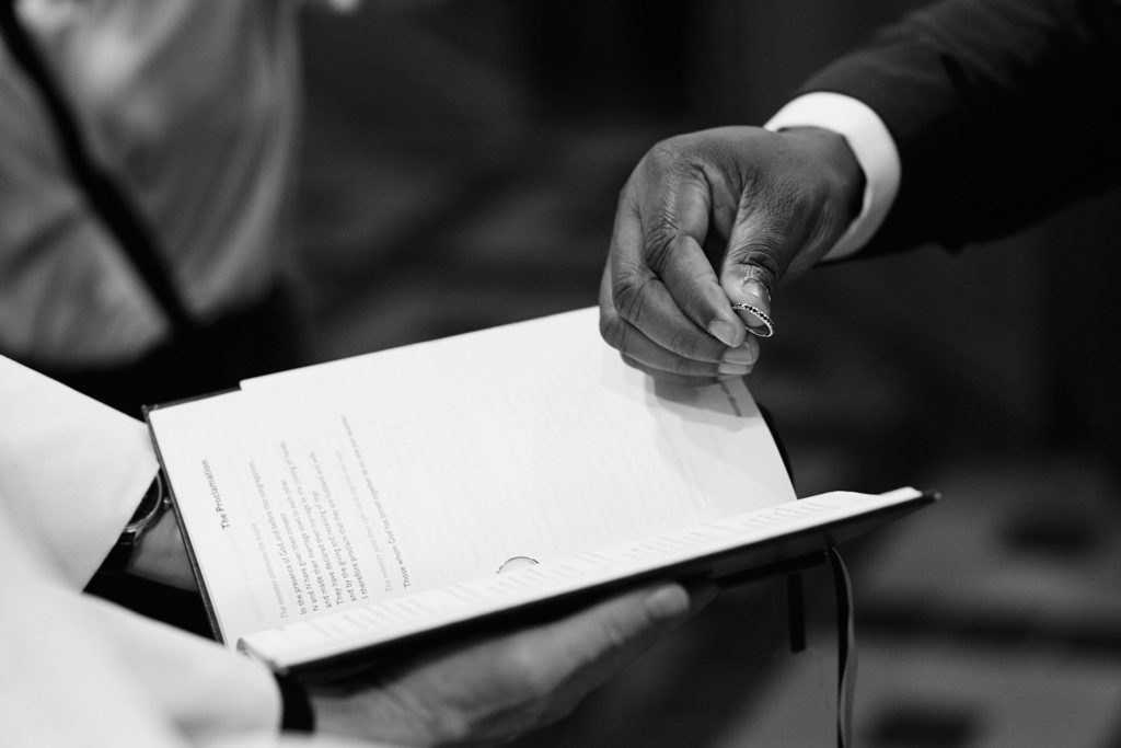 Black and white close-up of the groom holding an order of service