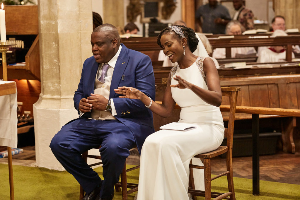 Bride and groom laughing as they sit together during the service