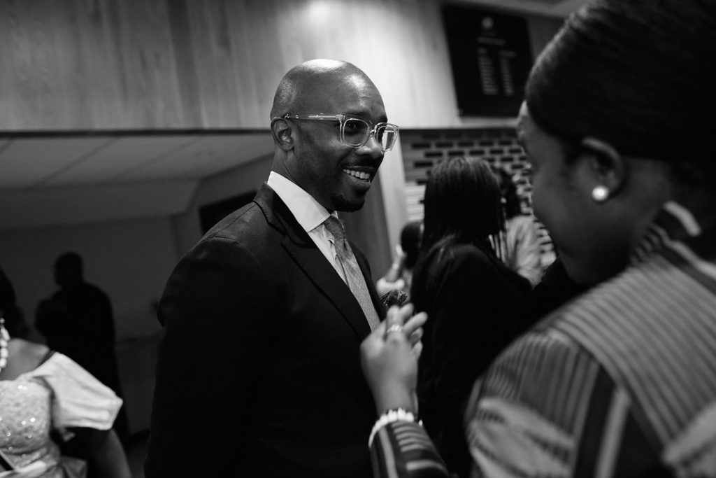 Black and white photo of a guest in a suit chatting at the reception