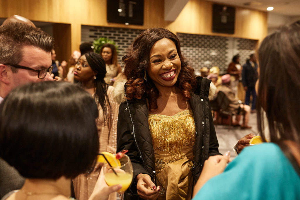 Wedding guest in a gold dress smiling at the reception