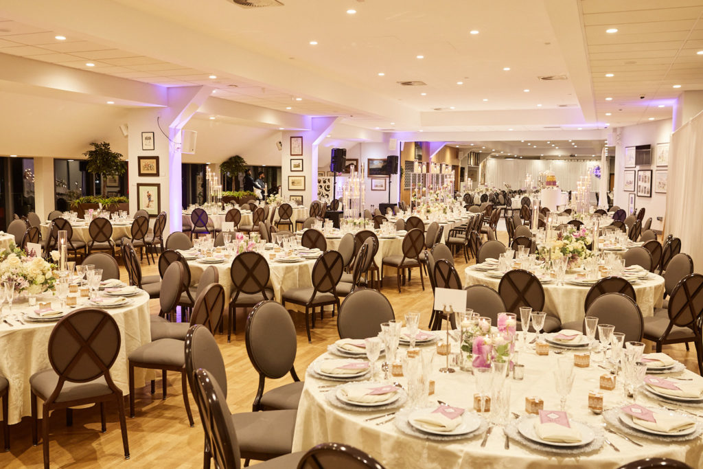 Reception room laid out with round tables and tall floral centrepieces