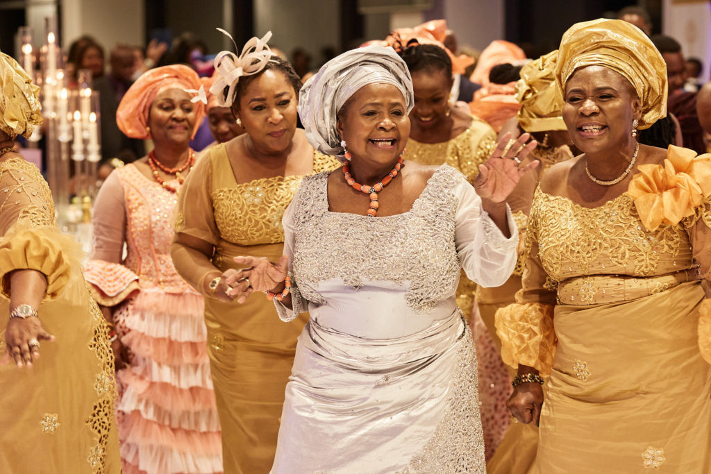 Women in matching gold lace outfits and head ties dancing together