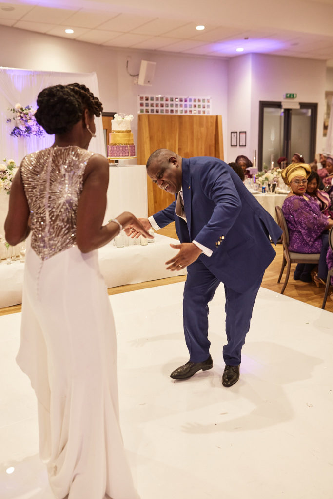 Groom dancing low in front of the bride on the dance floor