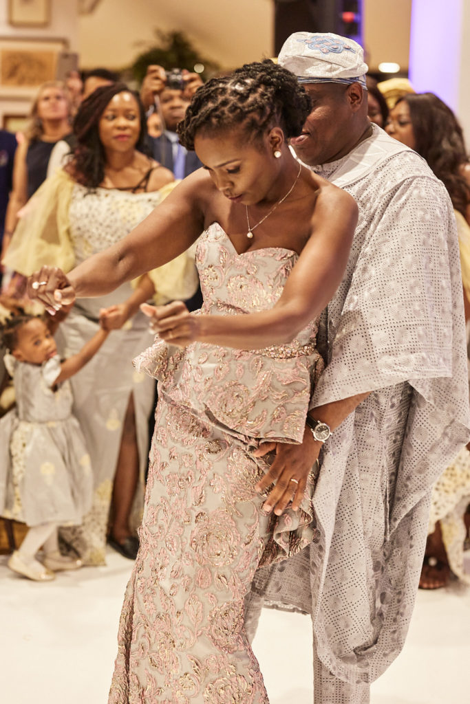 Bride dancing in a blush lace outfit as guests gather round