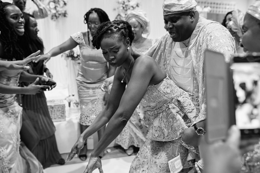 Black and white photo of the bride dancing low as guests cheer