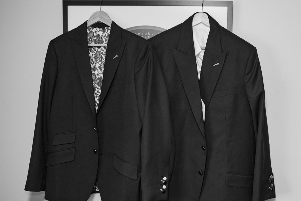 Two suit jackets hanging on a wardrobe door