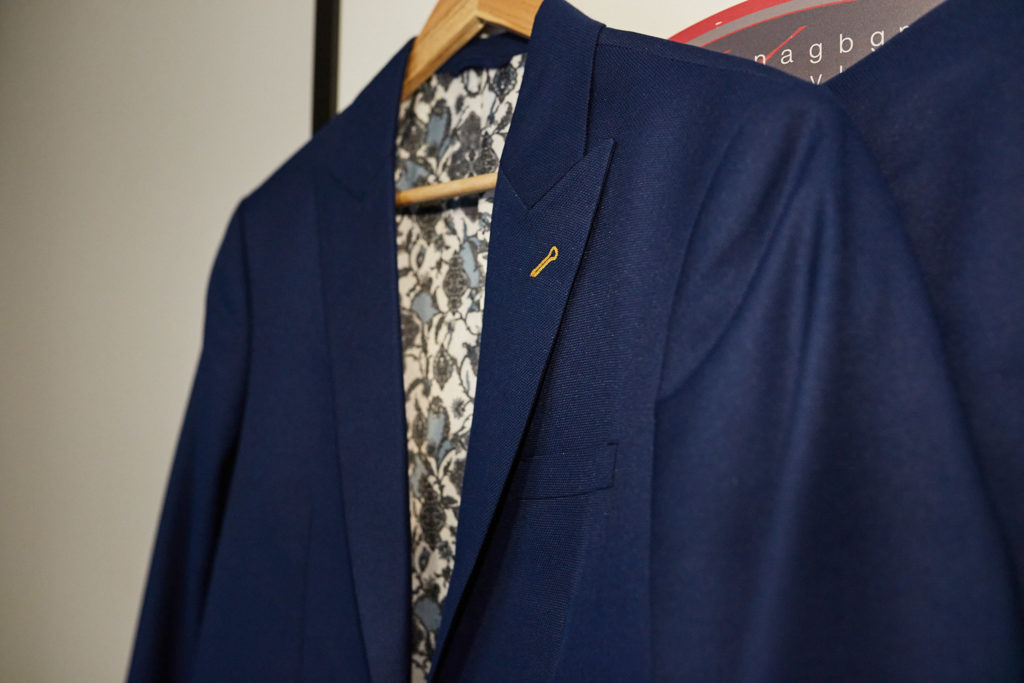 Navy suit jacket with a floral lining on a hanger